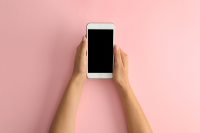 Photo of Woman holding modern phone on pink background, top view. Space for text