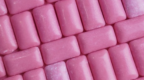 Photo of Many pink chewing gums as background, top view