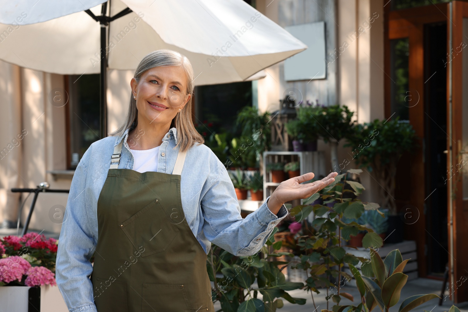 Photo of Happy business owner inviting to come into her flower shop outdoors, space for text