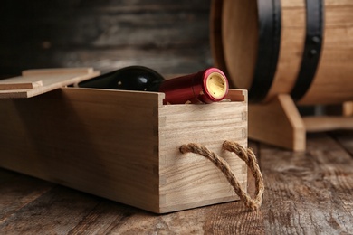 Photo of Crate with bottle of wine on wooden table