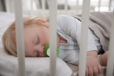 Cute little baby with pacifier sleeping in crib. Bedtime