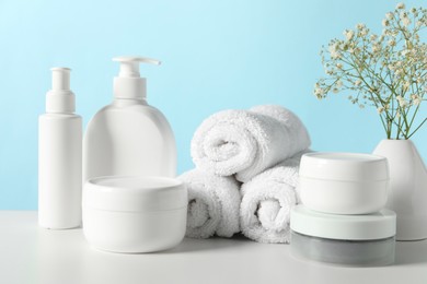 Photo of Different bath accessories and gypsophila on white table against light blue background, closeup