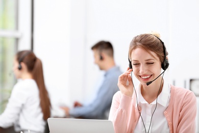 Photo of Young female receptionist with headset in office