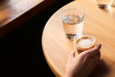 Photo of Woman with aromatic coffee at table in cafe, closeup