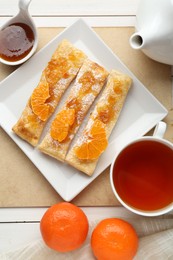 Photo of Fresh tasty puff pastry with sugar powder, jam and tangerines served on white wooden table, flat lay