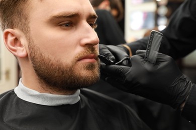 Photo of Professional hairdresser working with client in barbershop, closeup 