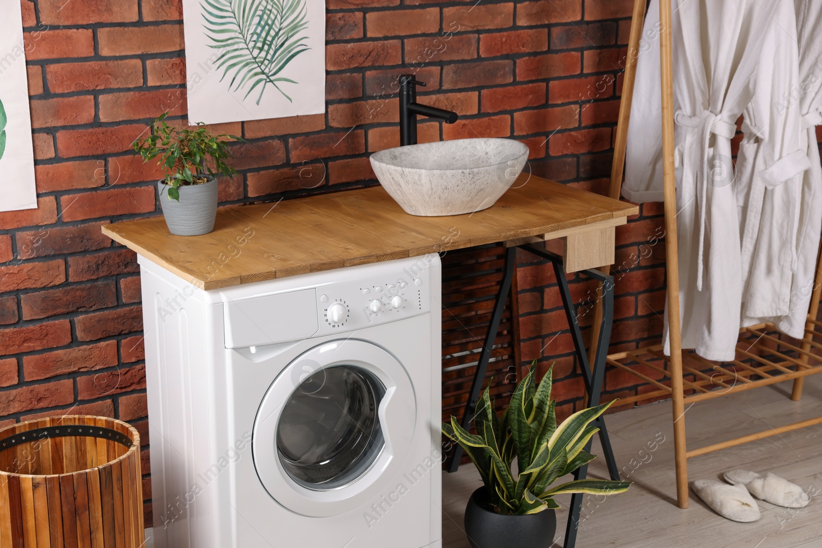 Photo of Washing machine and wooden rack with terry bathrobes indoors. Laundry room interior design