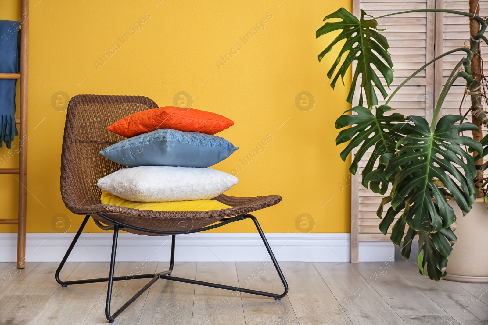 Photo of Armchair with different pillows near color wall in room