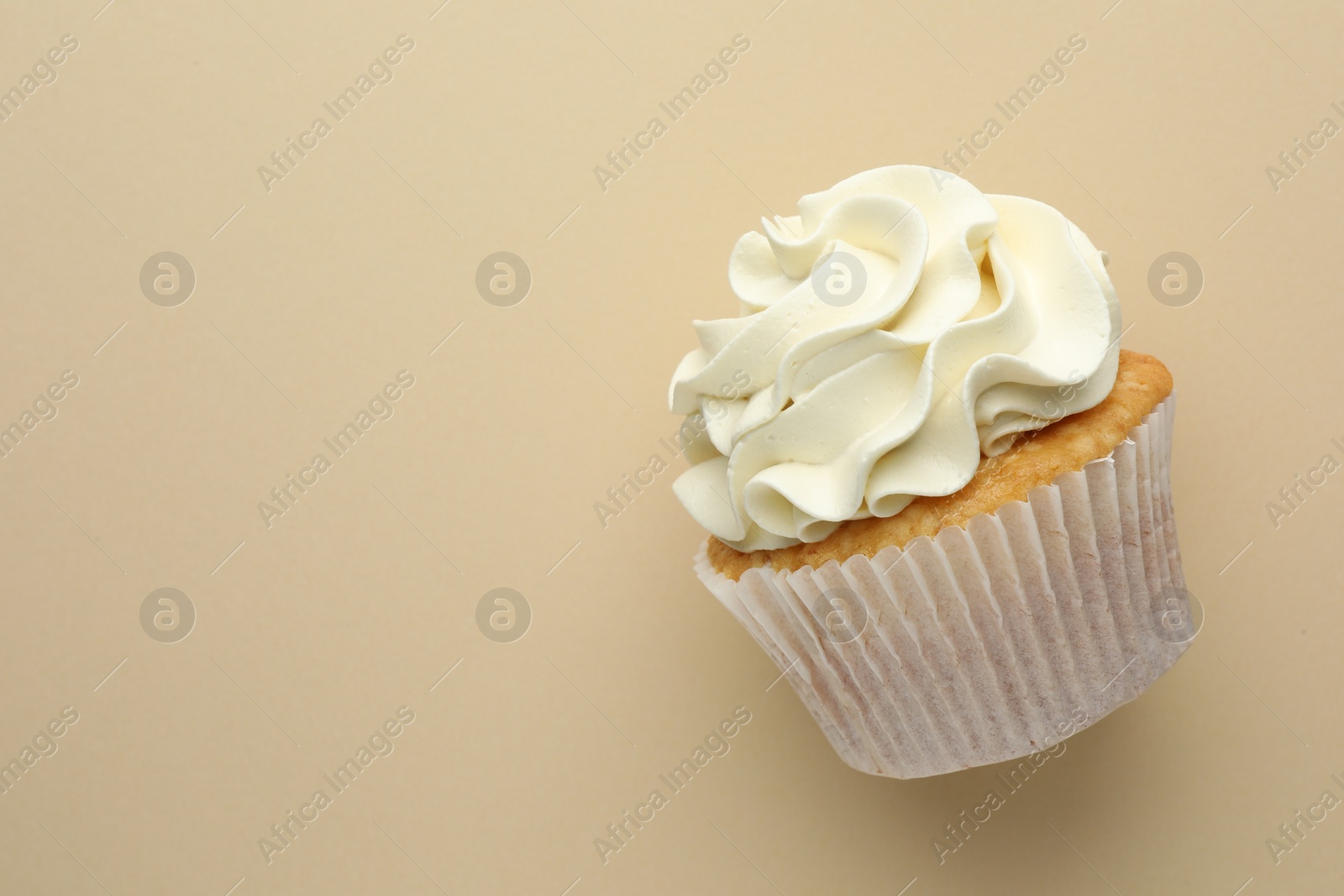 Photo of Tasty vanilla cupcake with cream on beige background, top view. Space for text