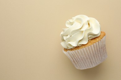 Photo of Tasty vanilla cupcake with cream on beige background, top view. Space for text