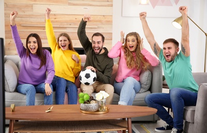 Group of friends celebrating victory of favorite soccer team in living room