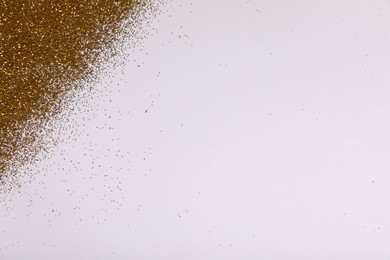 Photo of Shiny golden glitter on white background, top view