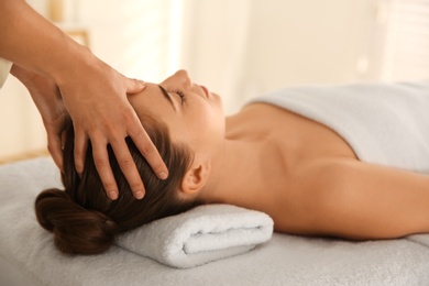 Photo of Young woman receiving head massage in spa salon