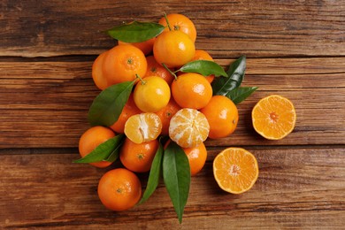 Photo of Fresh tangerines with green leaves on wooden table, top view
