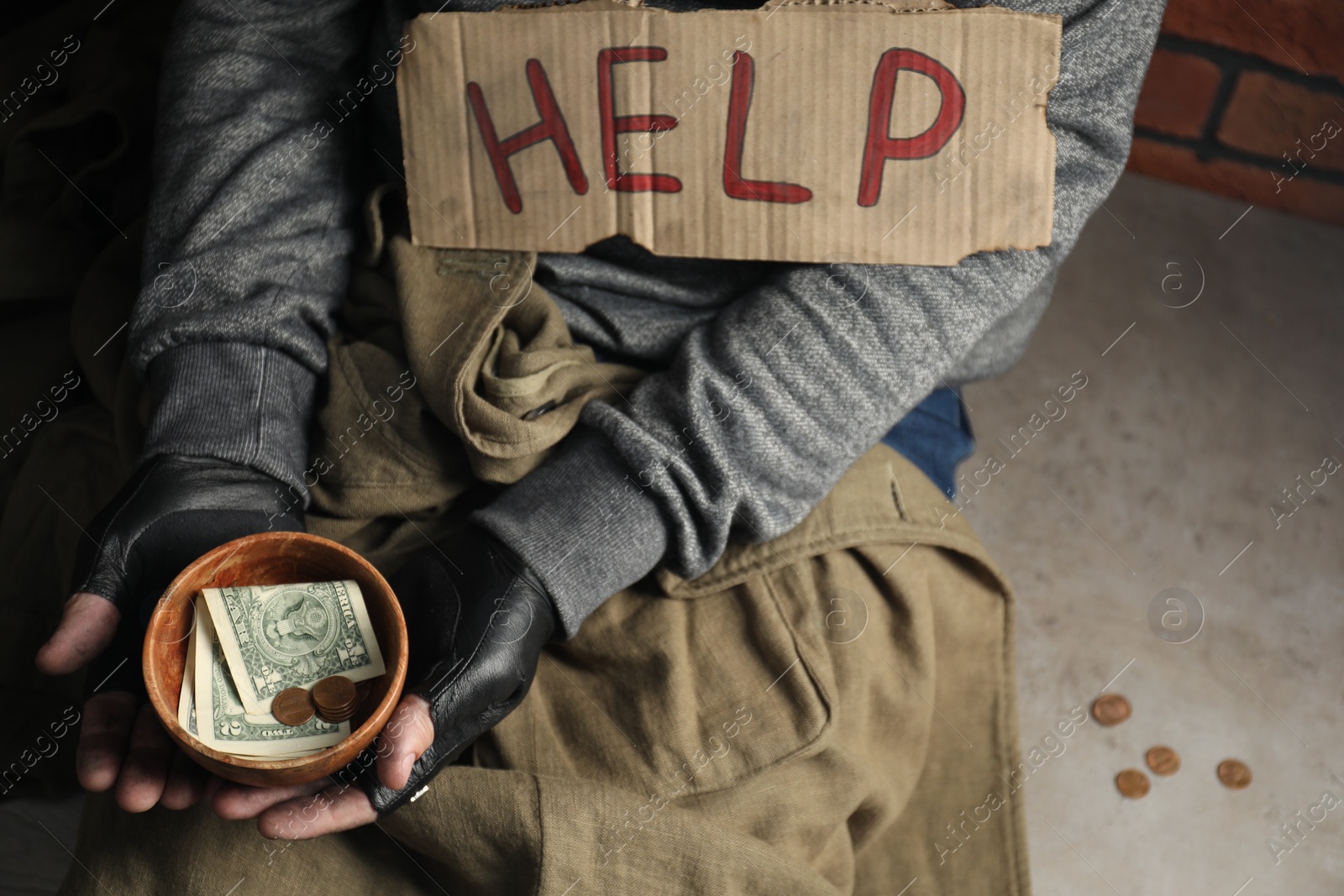 Photo of Poor homeless man with help sign holding bowl of donations on floor, above view