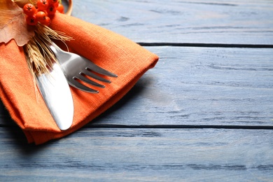 Photo of Cutlery with rowan berries on blue wooden table, closeup with space for text. Thanksgiving Day celebration