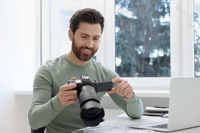 Photo of Professional photographer with digital camera at table indoors