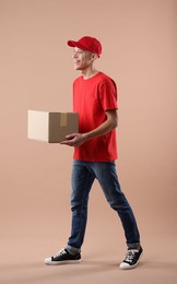 Photo of Happy courier with parcel on beige background