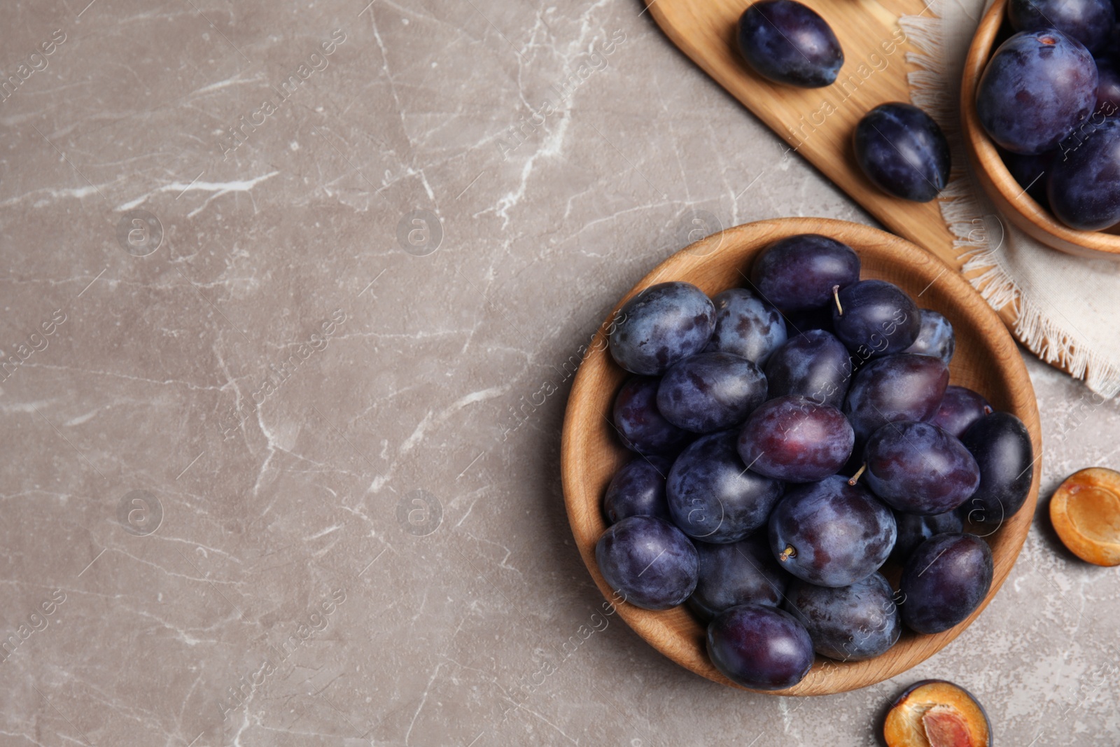 Photo of Delicious ripe plums on grey marble table, flat lay. Space for text