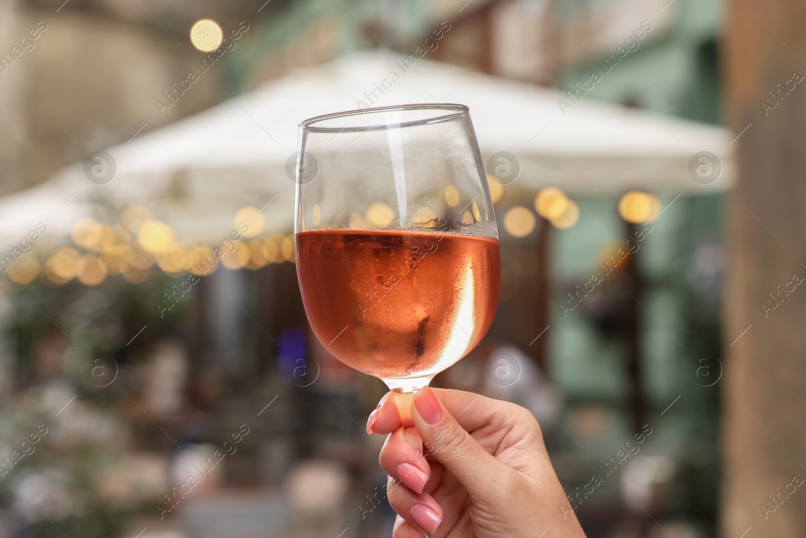 Photo of Woman holding glass of rose wine outdoors, closeup