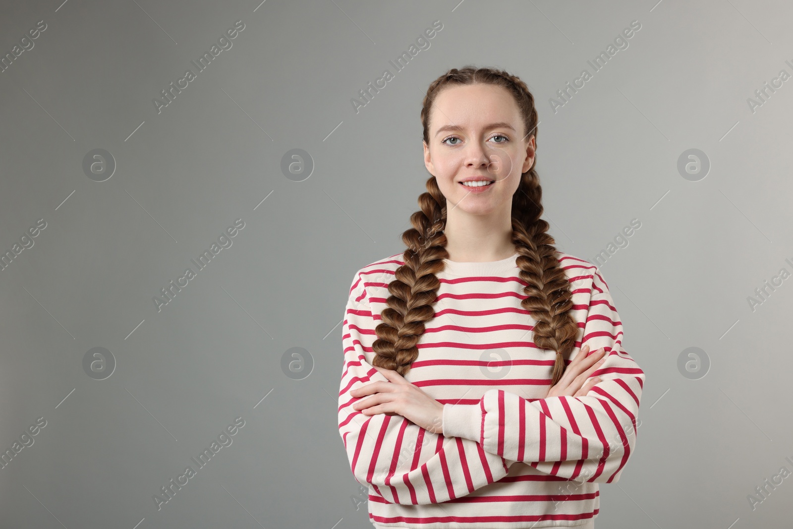 Photo of Woman with braided hair on grey background, space for text