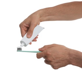 Man applying toothpaste on brush against white background, closeup