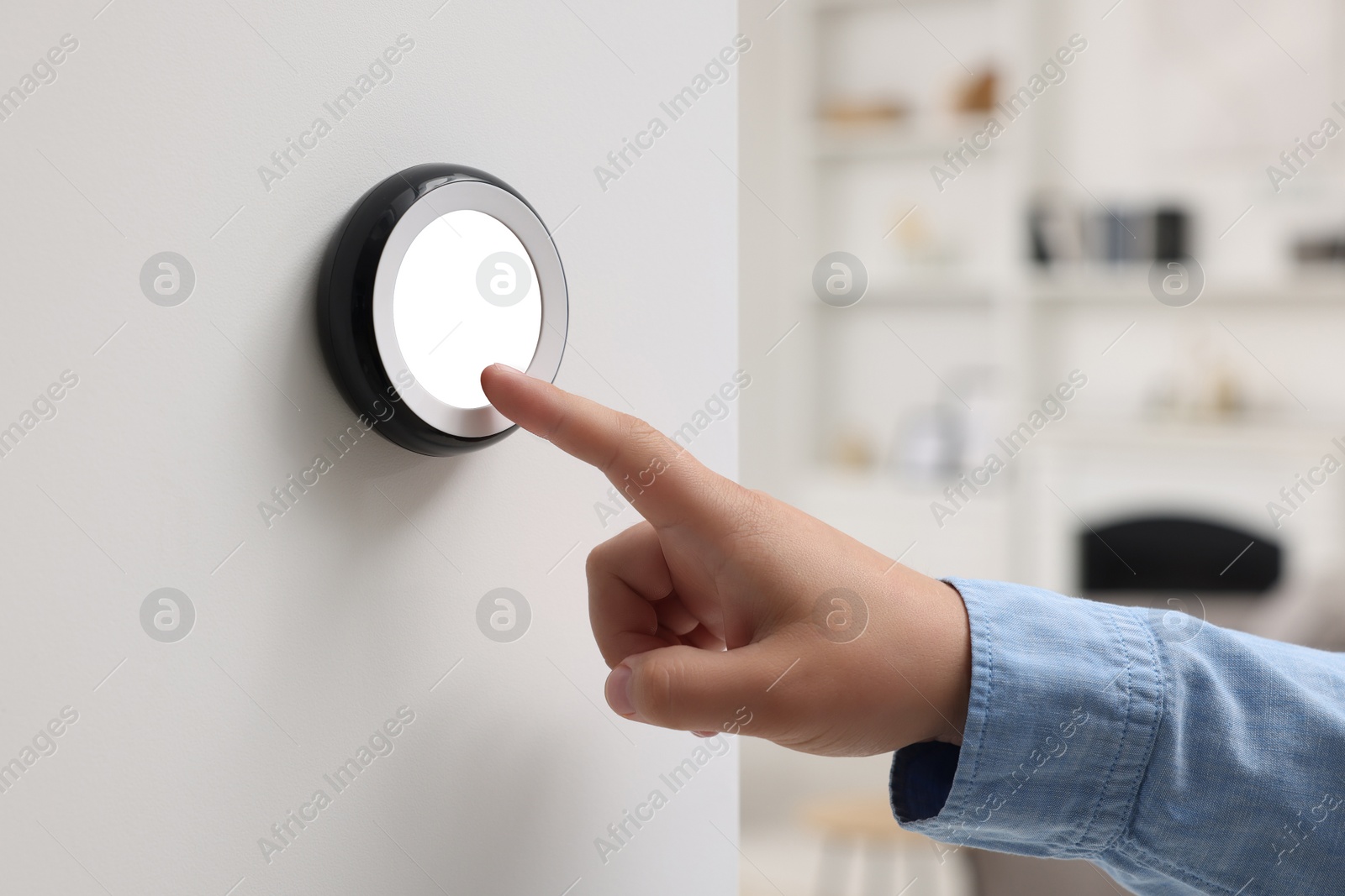 Photo of Woman adjusting thermostat on white wall indoors, closeup. Smart home system