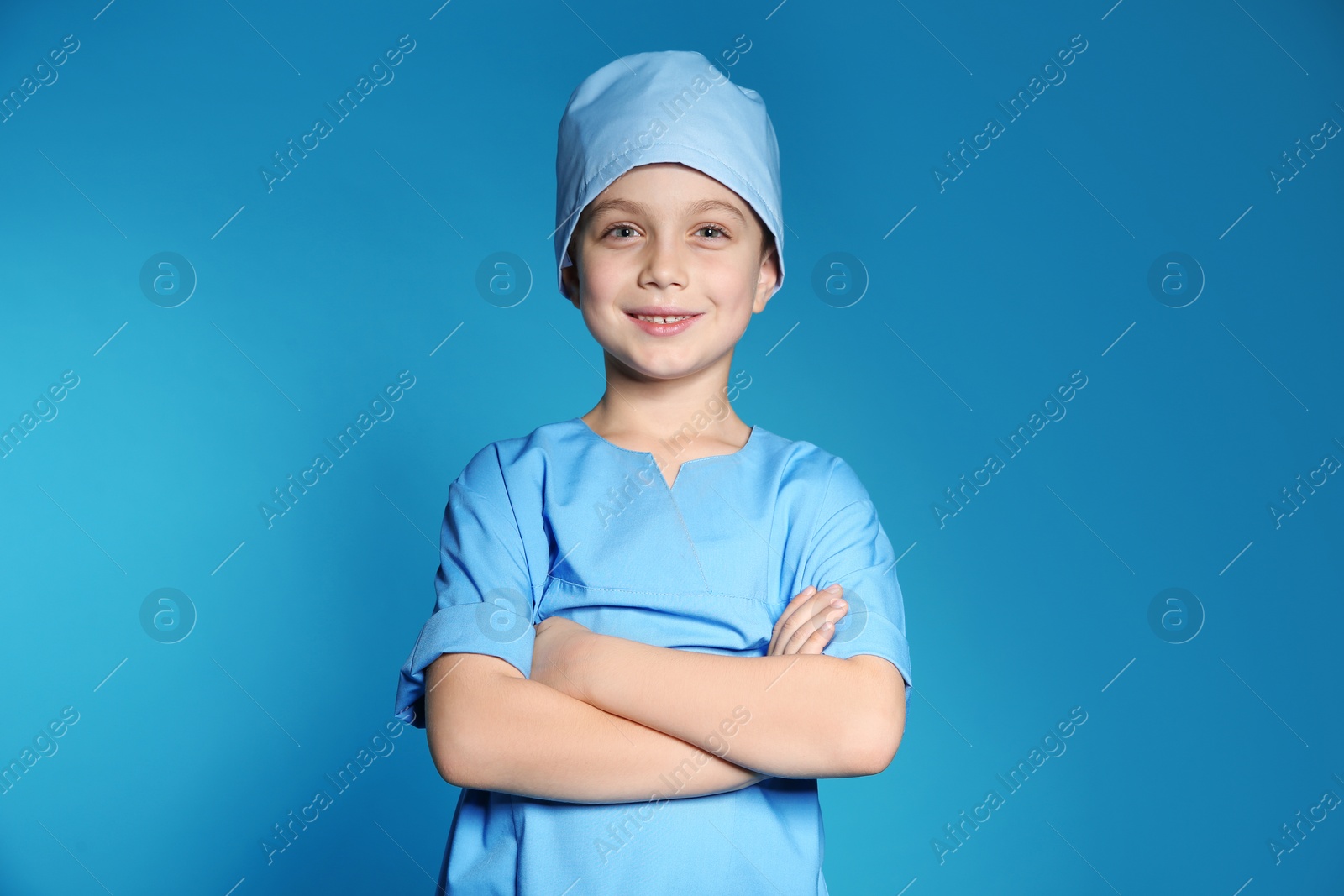 Photo of Cute little child in doctor uniform on color background