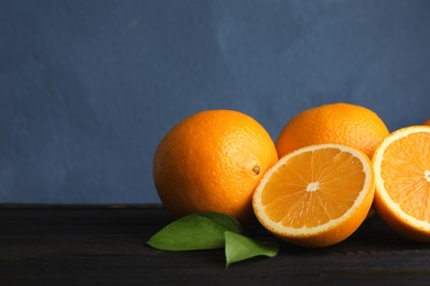 Fresh oranges with leaves on wooden table. Space for text