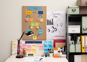 Photo of Business process planning and optimization. Workplace with lamp, colorful paper notes and other stationery on white wooden table