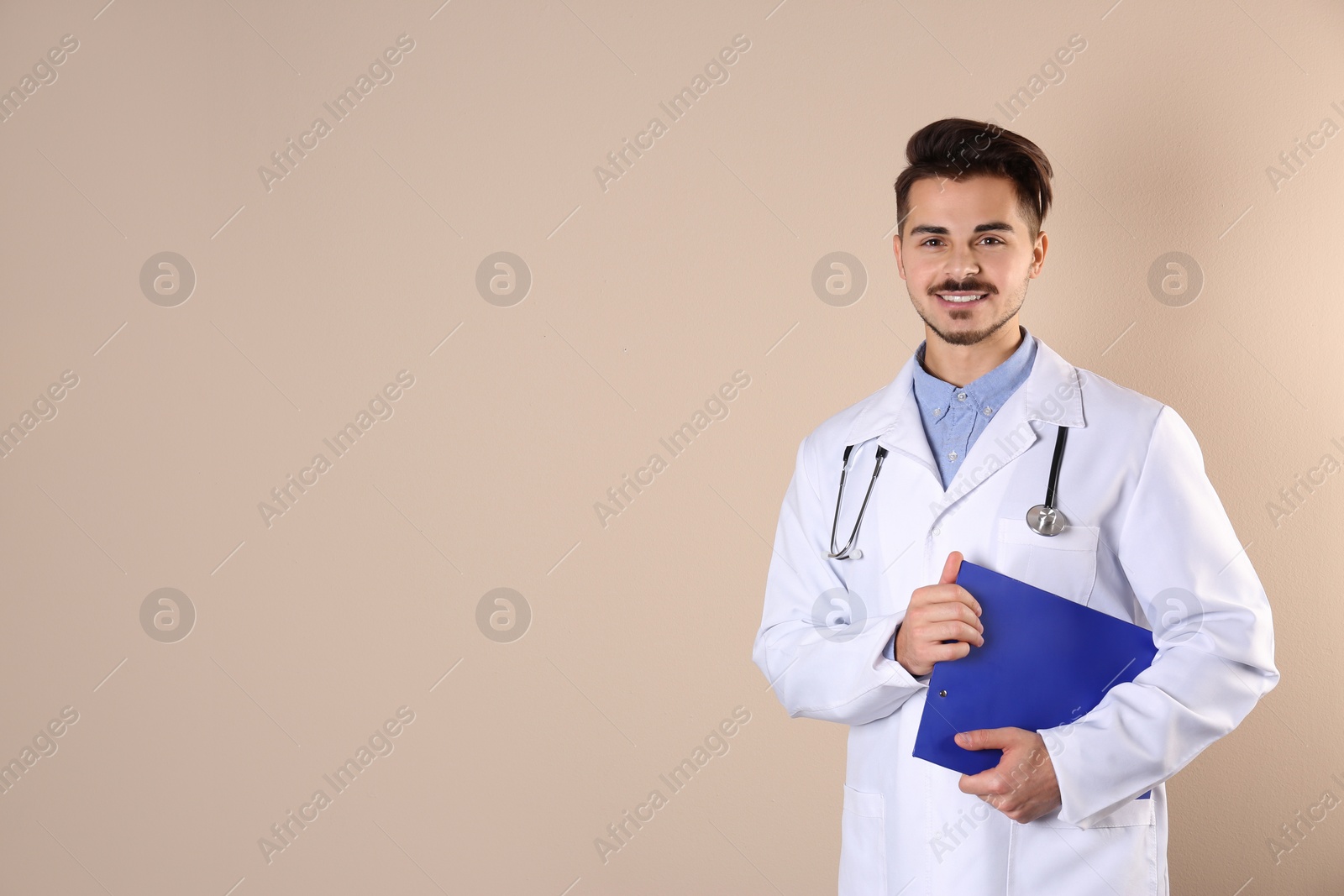 Photo of Young medical student with clipboard on color background. Space for text