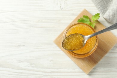 Fresh pike caviar in glass jar, parsley and spoon on white wooden table, top view. Space for text