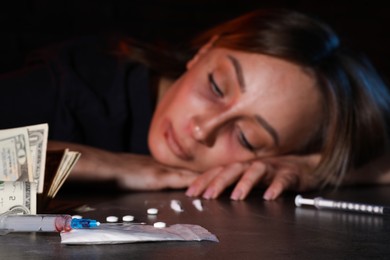 Photo of Addicted woman at table, focus on different drugs