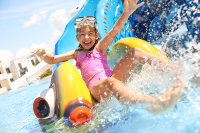 Little girl on slide at water park. Summer vacation