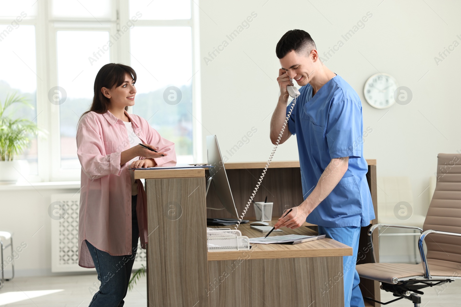 Photo of Smiling medical assistant working with patient at hospital reception