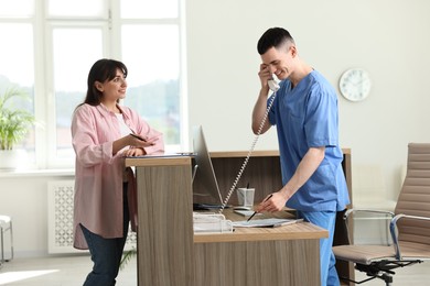 Smiling medical assistant working with patient at hospital reception