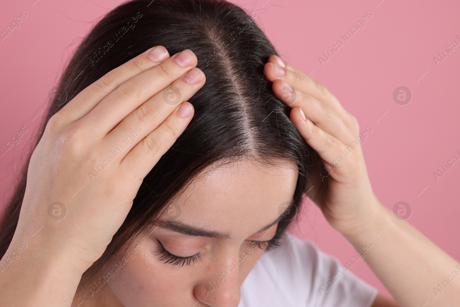 Photo of Woman examining her hair and scalp on pink background, closeup