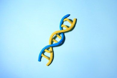 Photo of DNA molecule model made of colorful plasticine on light blue background, top view