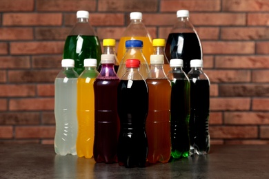 Photo of Bottles of soft drinks on table near brick wall