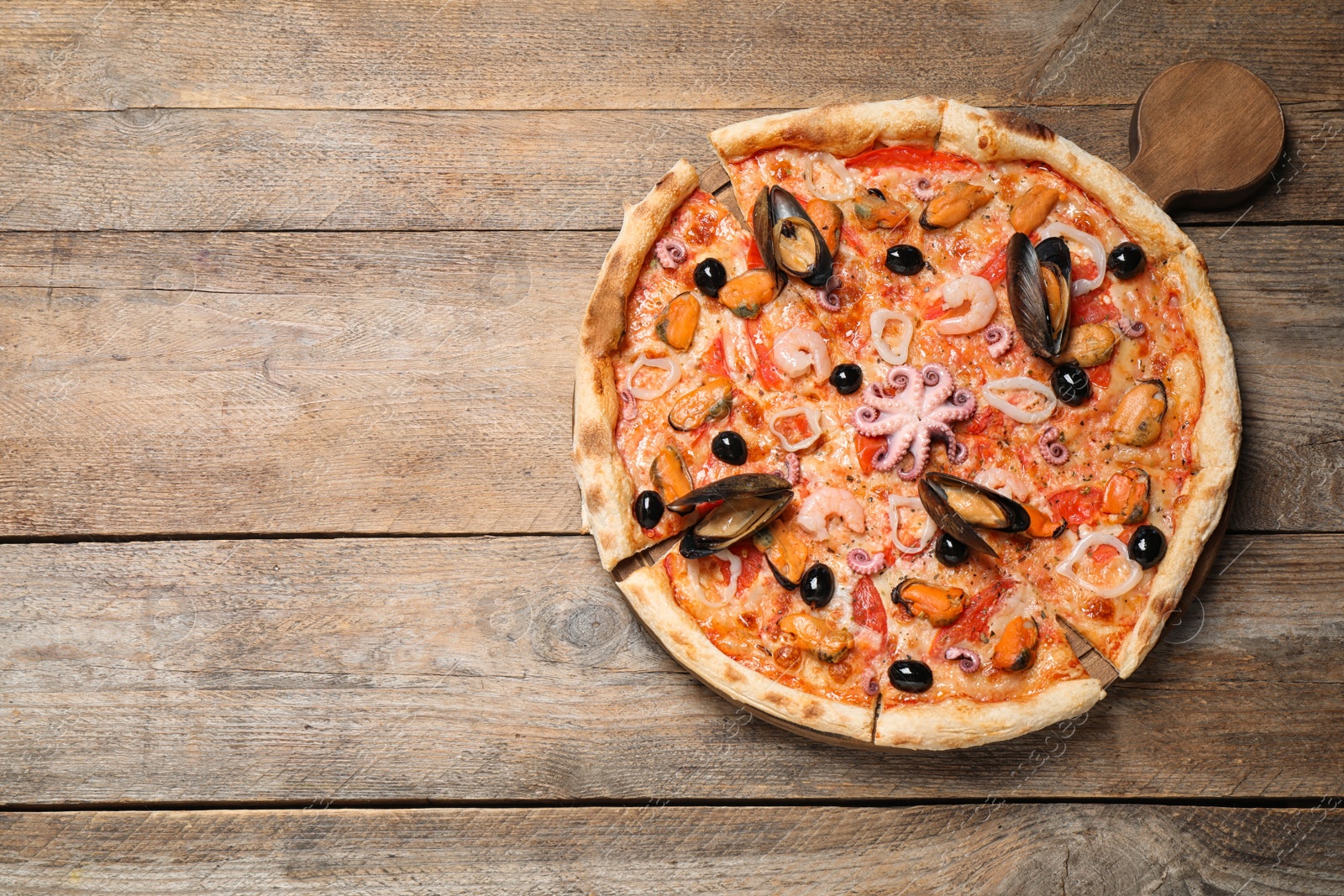 Photo of Tasty pizza with seafood on wooden table, top view. Space for text