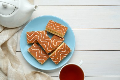 Photo of Tasty sponge cakes and hot drink on while wooden table, flat lay. Space for text