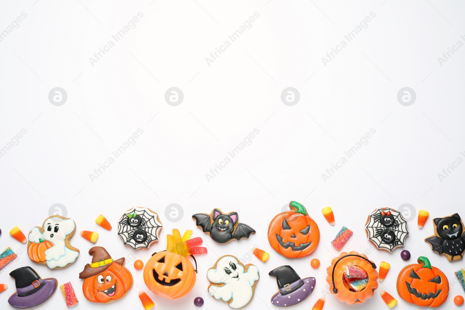 Photo of Tasty cookies and sweets for Halloween party on white table, flat lay. Space for text