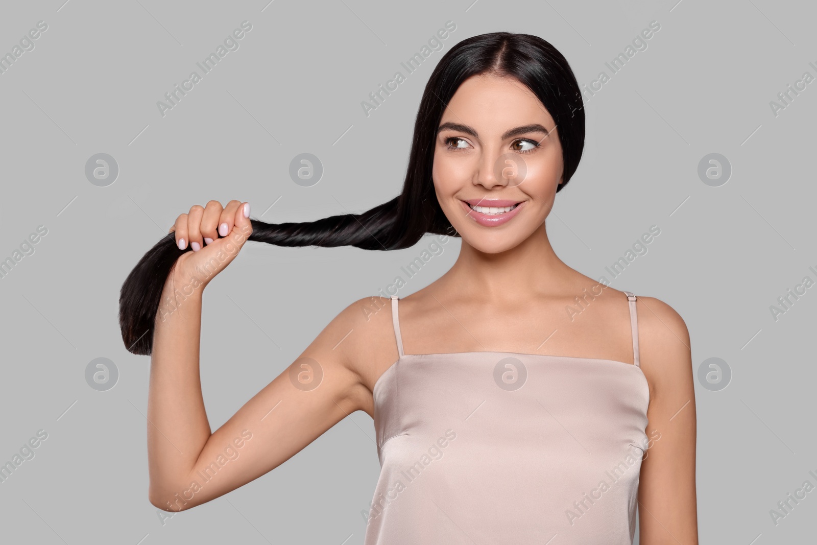 Photo of Portrait of beautiful young woman with healthy strong hair on light grey background