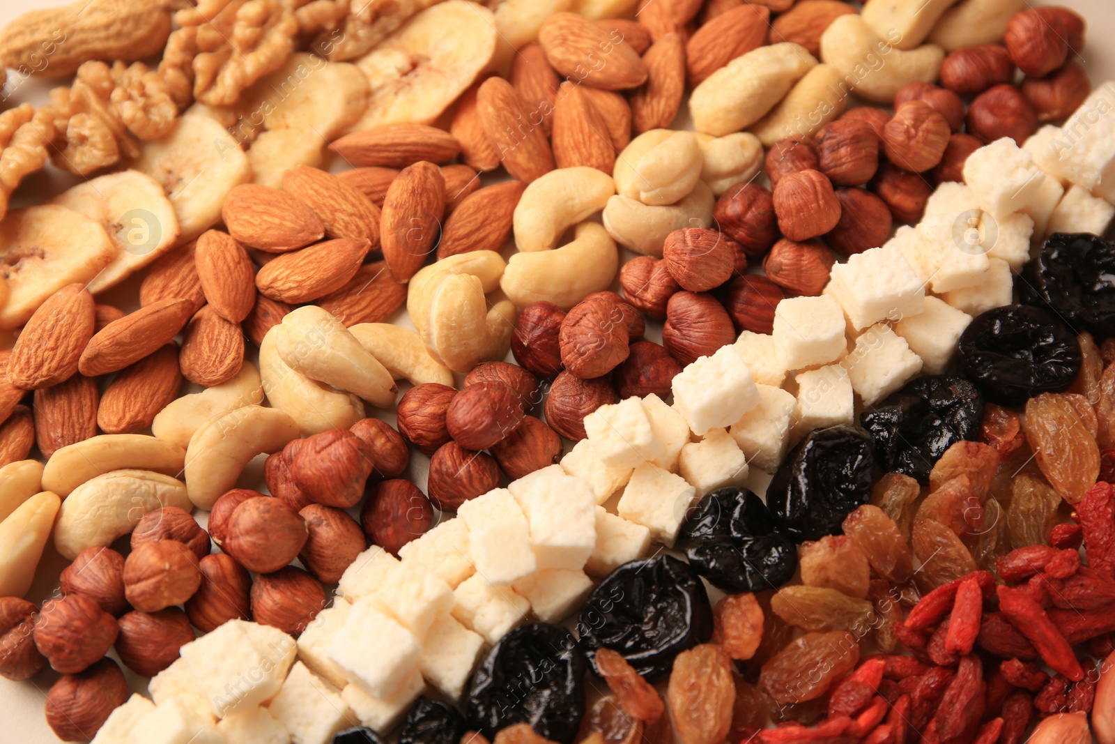 Photo of Different tasty nuts and dried fruits on beige background