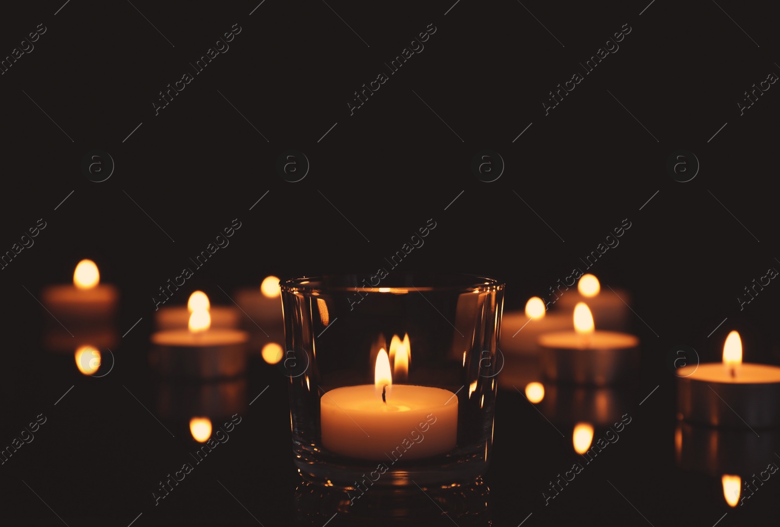 Photo of Beautiful burning wax candles on black background