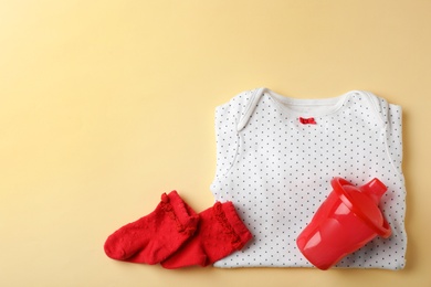 Photo of Stylish baby clothes and drinking cup on color background, top view. Space for text