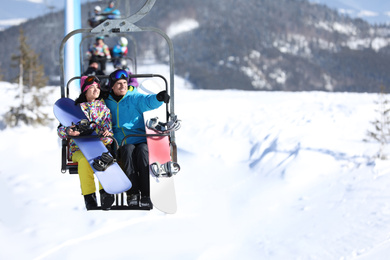 Photo of People using chairlift at mountain ski resort, space for text. Winter vacation