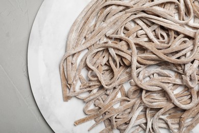 Photo of Uncooked homemade soba (buckwheat noodles) on grey table, top view