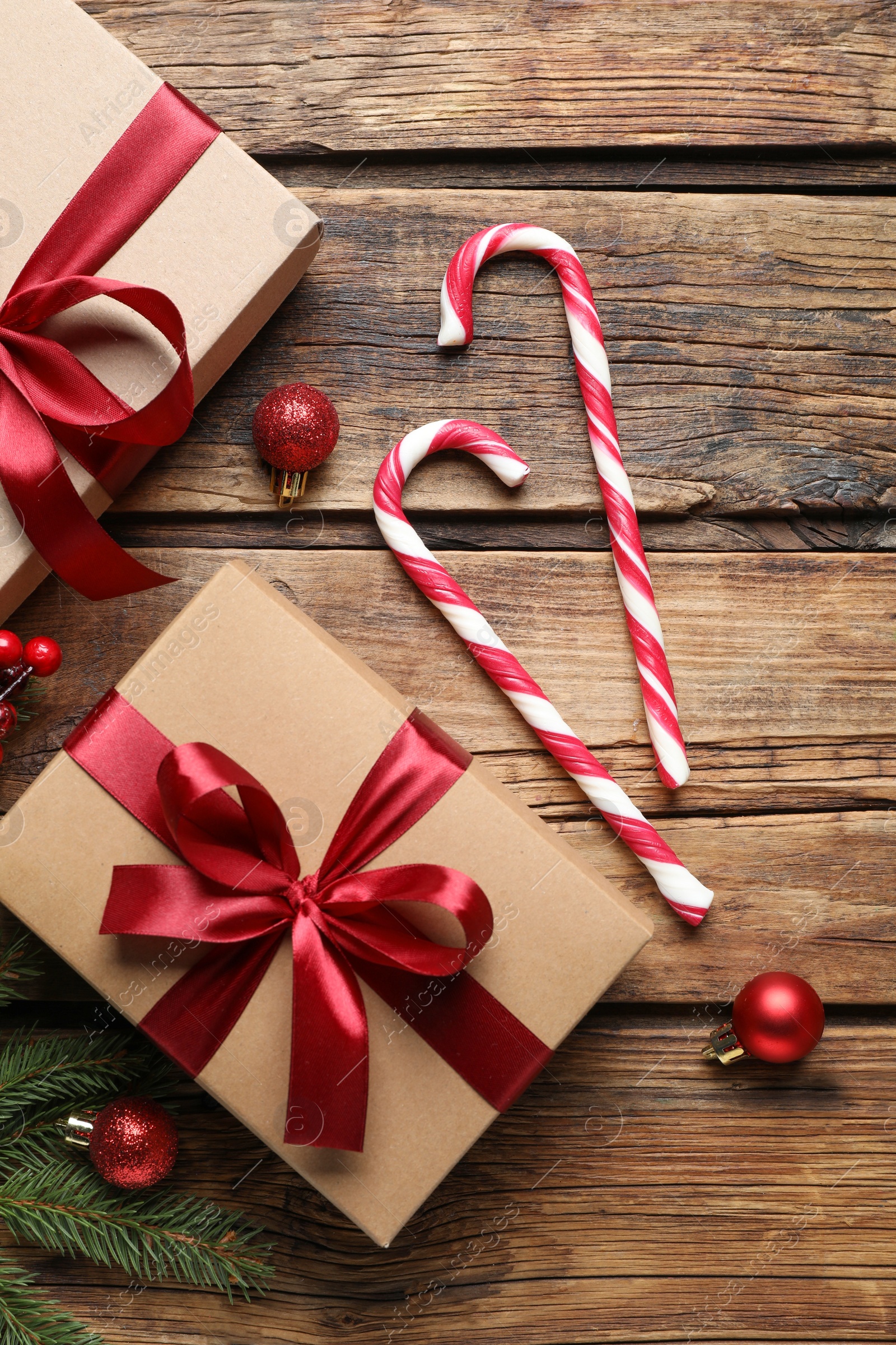 Photo of Gift box, candy canes and Christmas decor on wooden table, flat lay