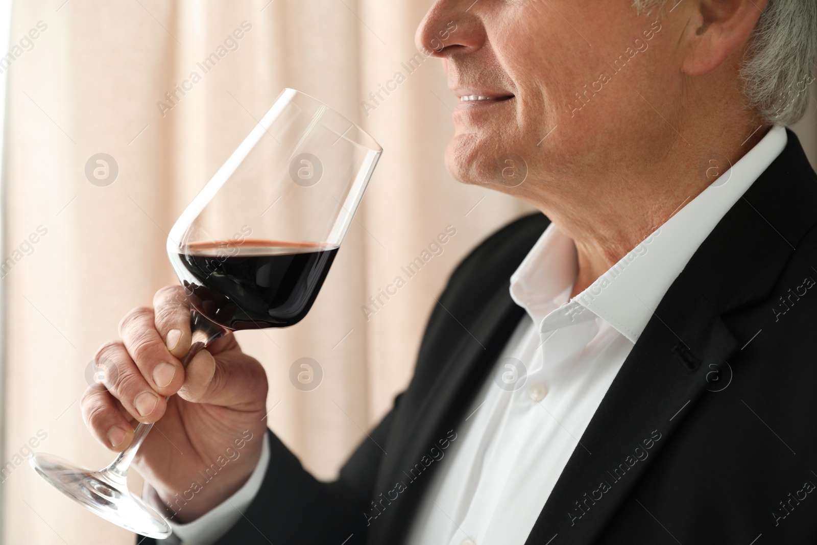 Photo of Senior man with glass of wine indoors, closeup